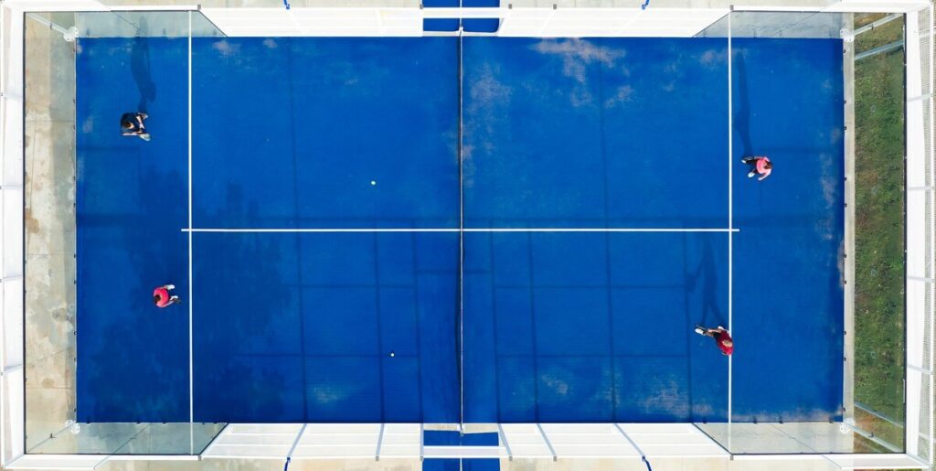 Aerial view of four players on an enclosed blue padel court